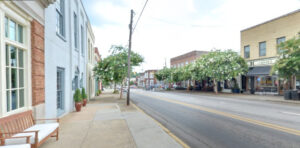 Small town streetscape, with trees, electrical poles, and two-story buildings lining both sides of the street